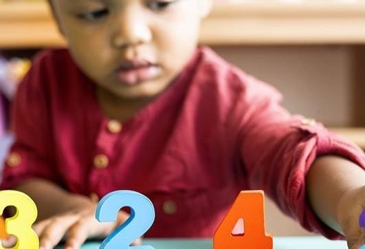 A toddler plays with wooden number blocks