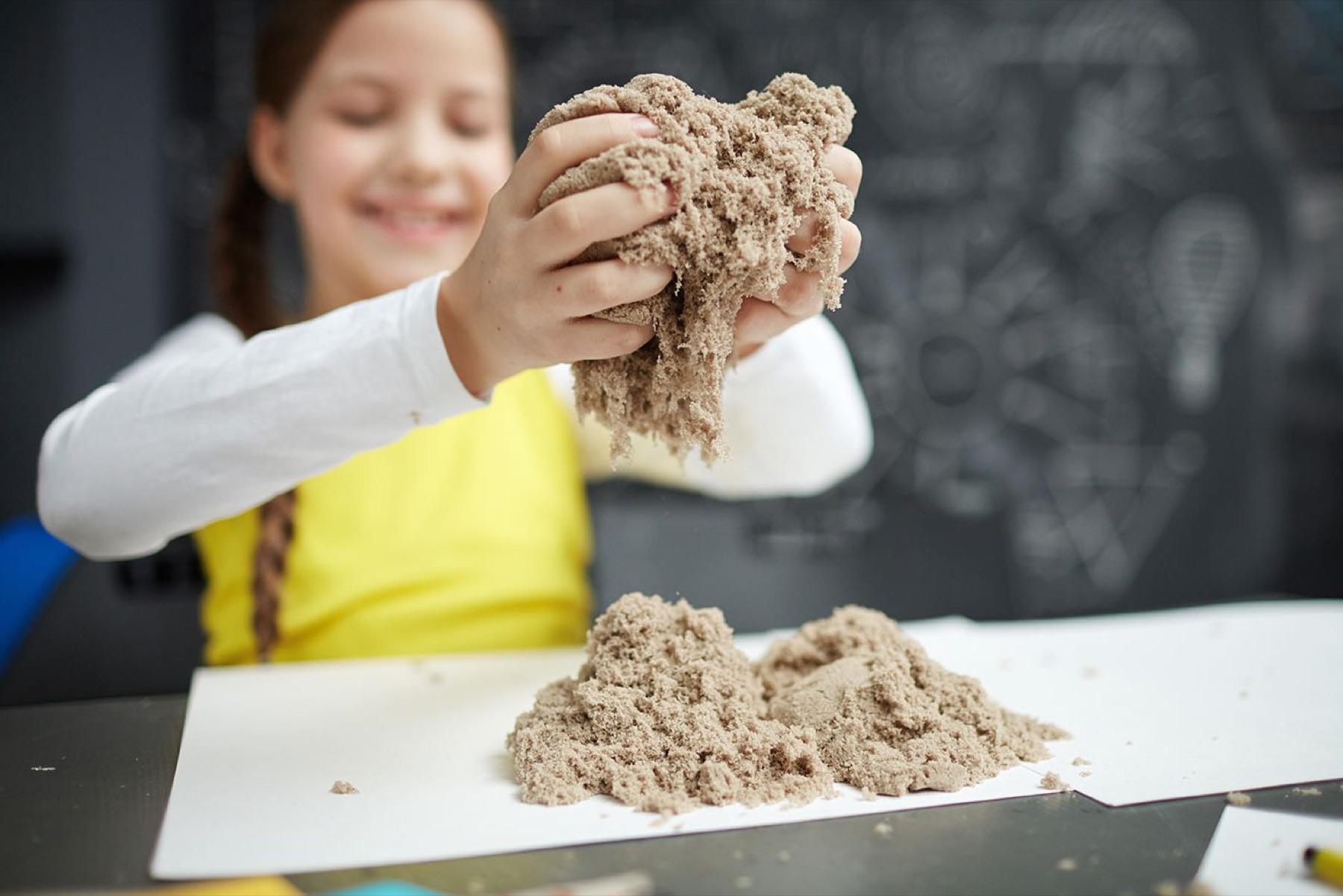 A child plays with sensory sand at a table